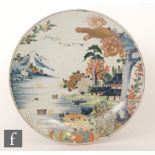 A large early 20th Century Japanese charger decorated with a gilt dragon looking over a garden and