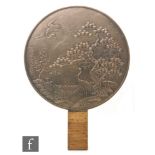 A late 19th Century Japanese bronze circular mirror decorated in relief with cranes by a bonsai