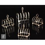 Four hallmarked silver four division toast racks, three raised on four ball feet,