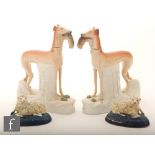 A pair of 19th Century Staffordshire flatback models of whippets stood with rabbits in their mouths