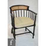 A 20th Century ebonised cane back and seat bobbin turned elbow chair.