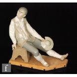 A Lladro figurine of Sancho Panza seated on a stool, looking over his shoulder and holding his hat,