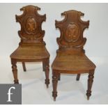 A pair of Victorian oak hall chairs with carved scroll panel backs above solid seats and turned