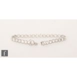 A contemporary 18ct white gold diamond tennis bracelet comprising thirty two brilliant cut,