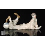 A Lladro figure of a clown, reclining with his feet on a beach ball, model 4618, printed mark,