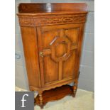 A 17th Century style oak floorstanding corner cupboard enclosed by a geo-metric door below a ledge