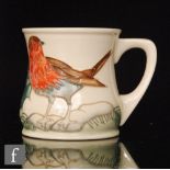 A Moorcroft Pottery mug decorated with a tubelined robin perched on a holly branch, impressed mark,