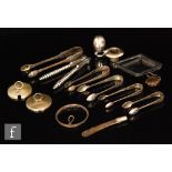 Five pairs of silver sugar tongs, a silver pepper, a pair of plated nutcrackers,