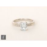 A modern 9ct hallmarked white gold aquamarine and diamond ring, central emerald cut,