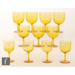 A set of seven golden amber wine glasses with ribbed ovoid bowls and circular spread foot,