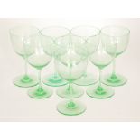 A set of six Edwardian uranium green wine glasses with ovoid bowls and narrow stems over a circular