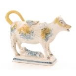 An early 19th Century Prattware cow creamer and cover with recumbent calf beneath,