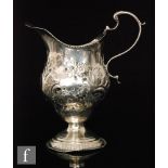 An 18th Century hallmarked silver pedestal baluster cream jug with scroll handle and domed foot,