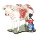 An early 19th Century cow creamer and cover with a seated milkmaid and pail beneath,