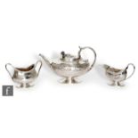 Omar Ramsden & Alwyn Carr - A hallmarked silver three piece pedestal boat shaped tea set of plain