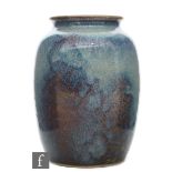 Ruskin Pottery - A high fired vase of barrel form with a roll rim neck decorated in a mottled green