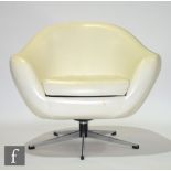 Unknown - A cream coloured vinyl upholstered bucket shaped swivel armchair with a loose insert