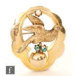 A 19ct Century oval brooch with a central bird above two claw set emeralds and below a single pearl,