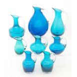 A collection of eight Whitefriars glass jugs in cased blue and kingfisher blue with applied clear