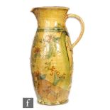 A 20th Century art pottery pitcher of slender ovoid form, with undulating scroll handle,