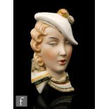 A 1930s Royal Dux wall mask modelled as a blonde lady wearing a white hat and scarf in shades of