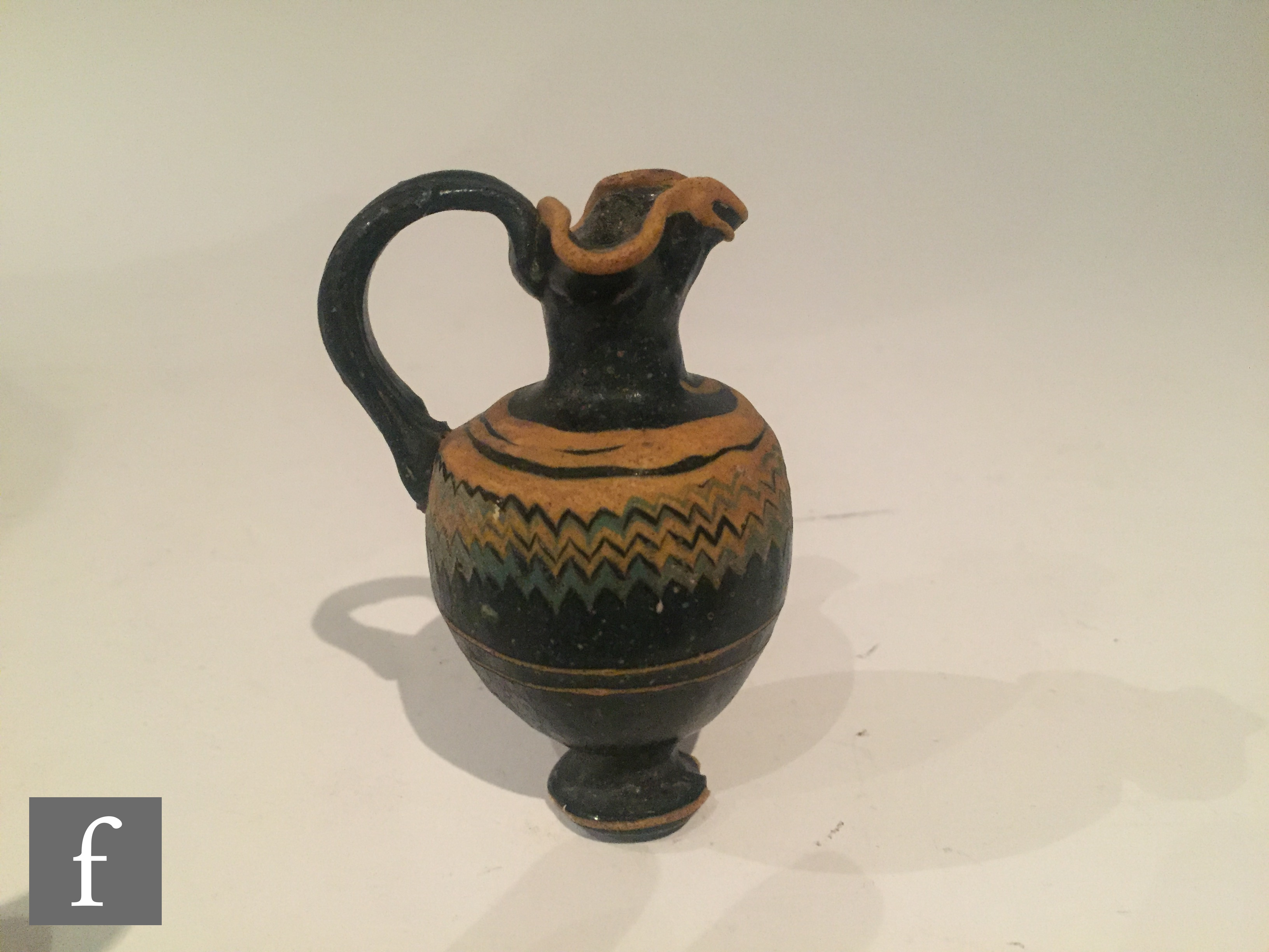Roman 2nd to 4th Century AD - A miniature dark black glass jug with multi yellow zig zag bands of - Image 4 of 7