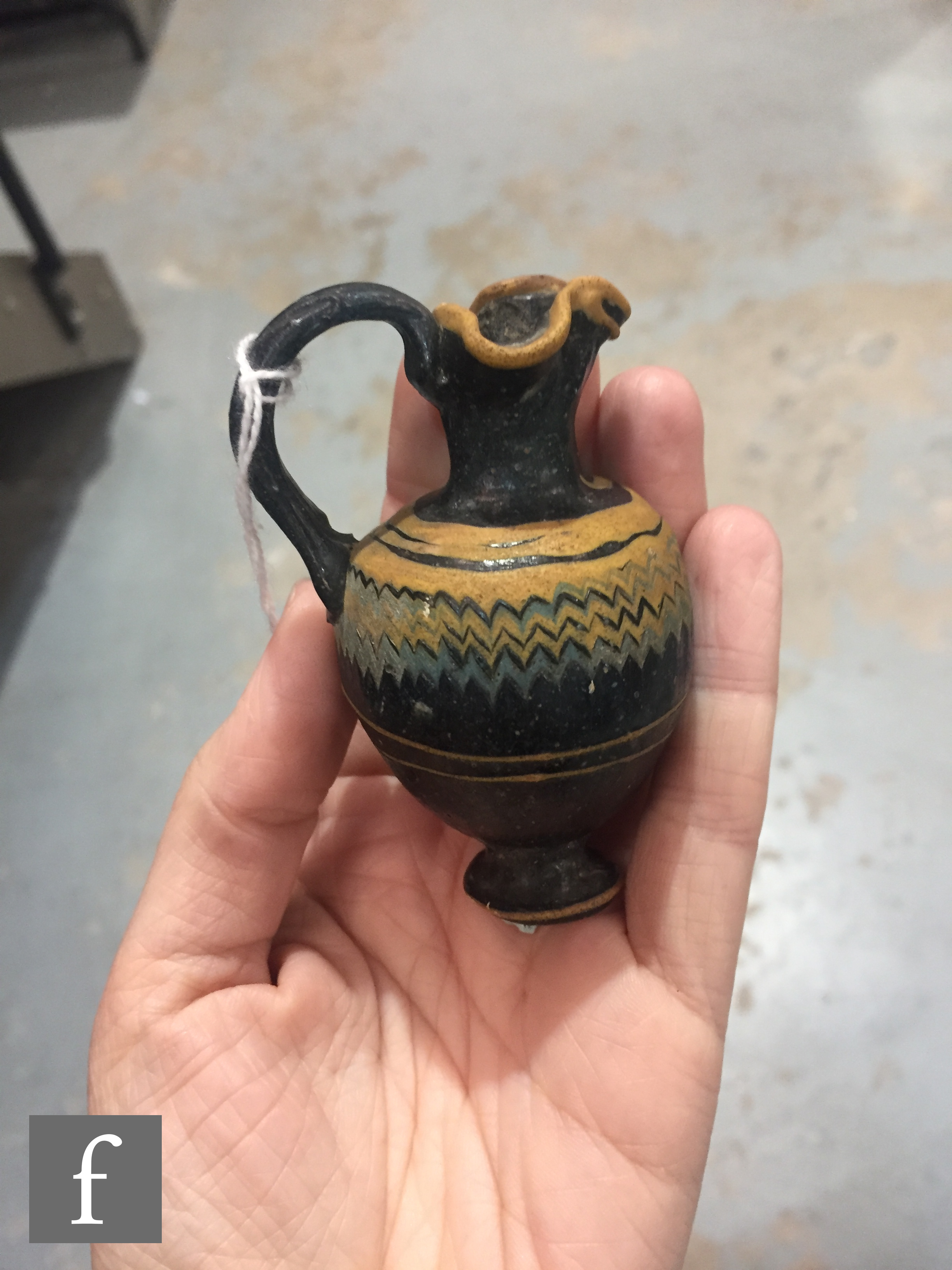 Roman 2nd to 4th Century AD - A miniature dark black glass jug with multi yellow zig zag bands of - Image 7 of 7