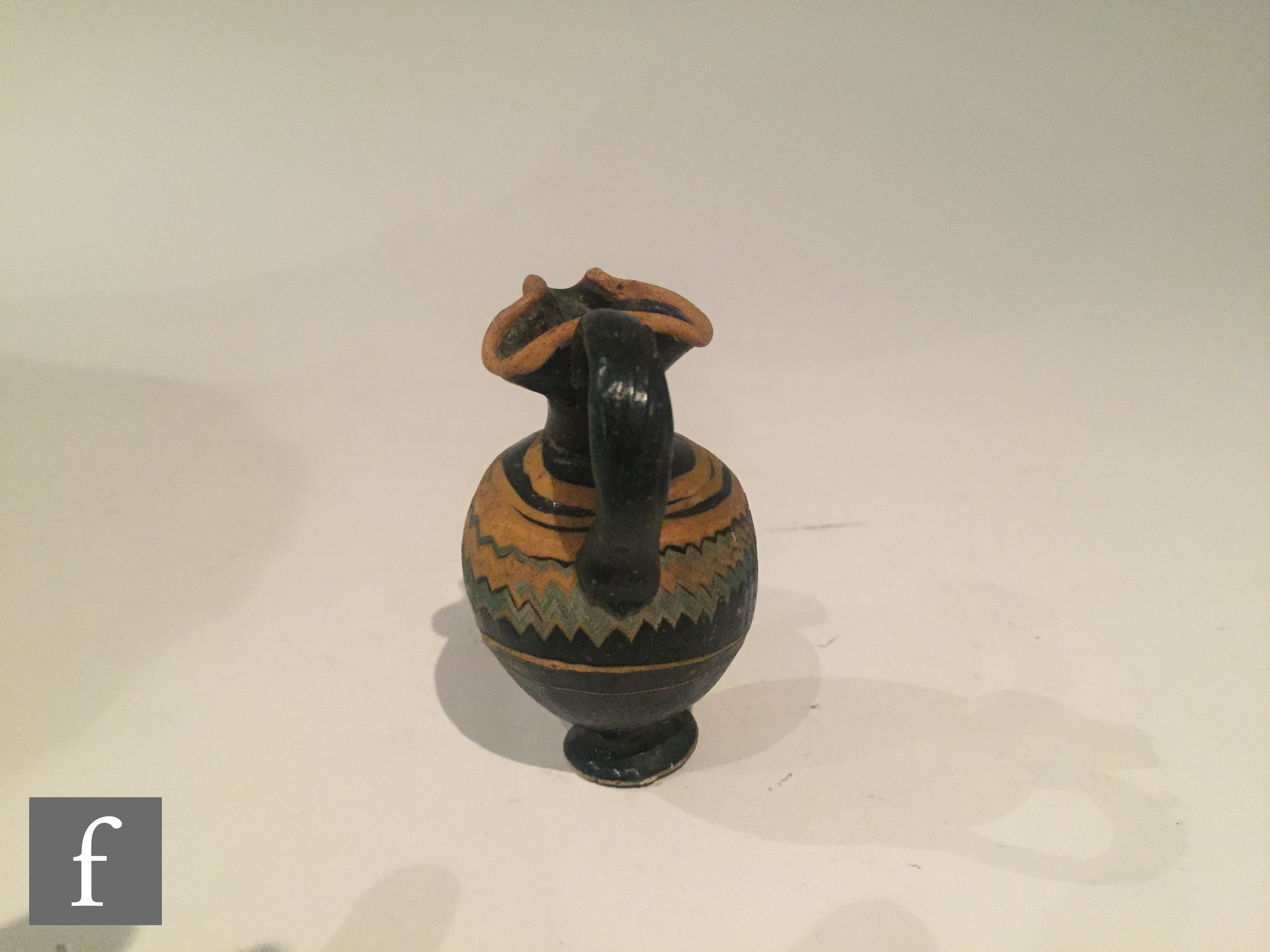 Roman 2nd to 4th Century AD - A miniature dark black glass jug with multi yellow zig zag bands of - Image 3 of 7