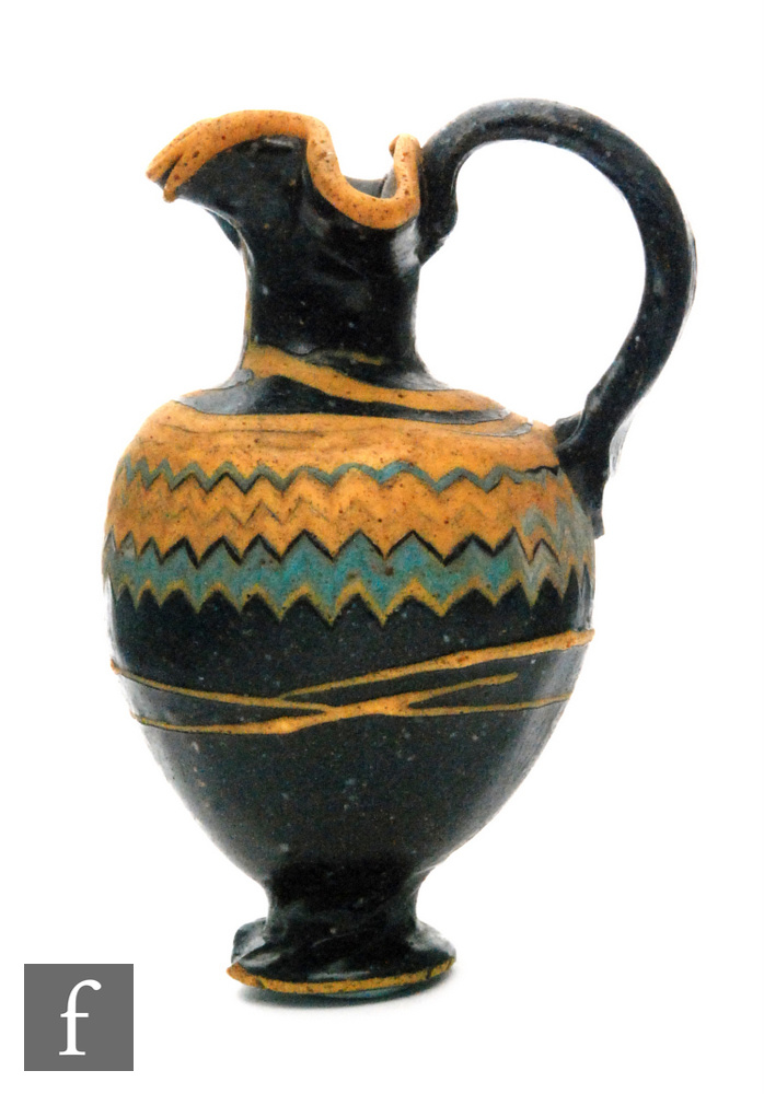 Roman 2nd to 4th Century AD - A miniature dark black glass jug with multi yellow zig zag bands of