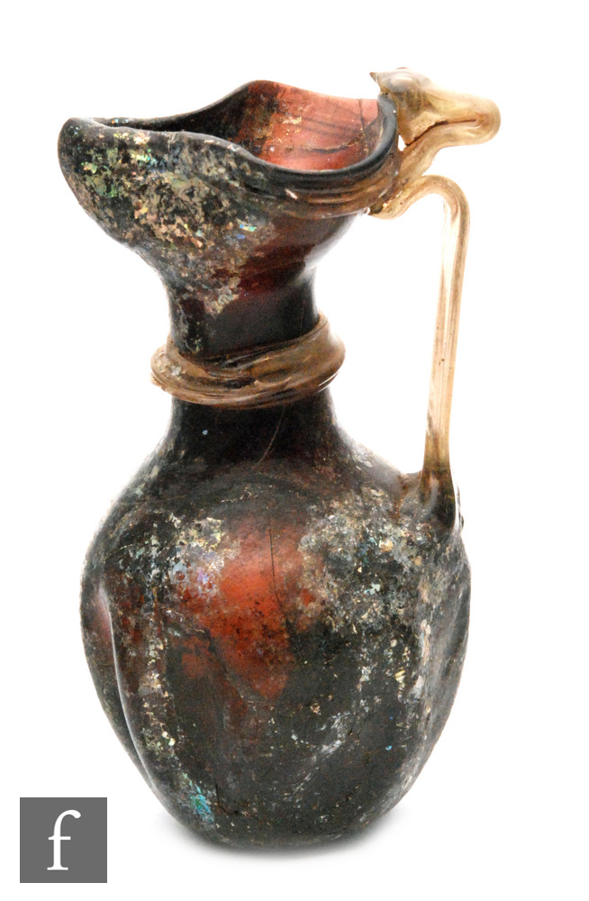 Roman 2nd to 4th Century AD - An iridescent deep amber glass jug with applied clear ribbed handle,