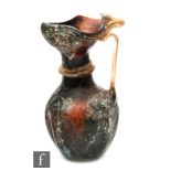 Roman 2nd to 4th Century AD - An iridescent deep amber glass jug with applied clear ribbed handle,
