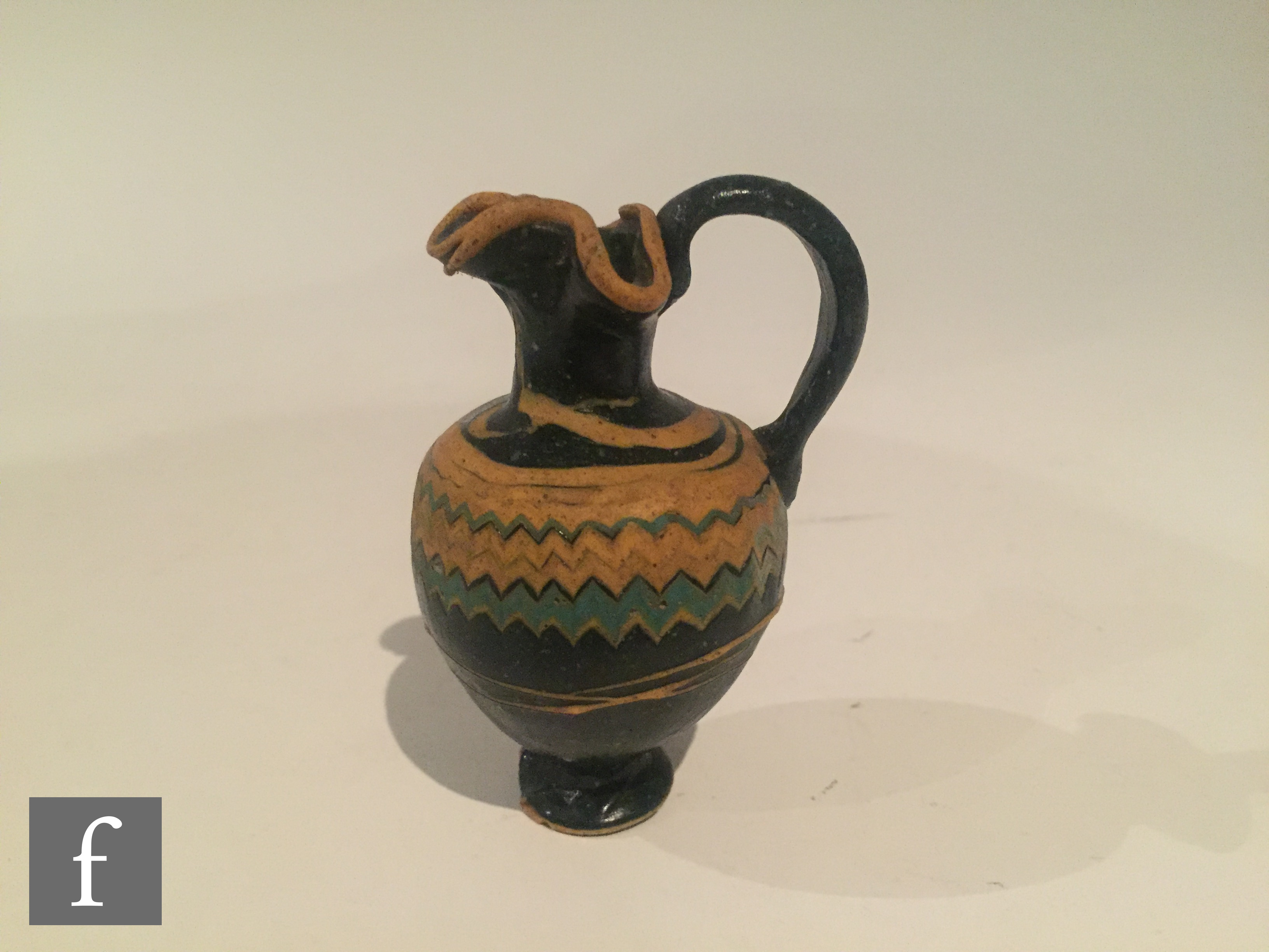 Roman 2nd to 4th Century AD - A miniature dark black glass jug with multi yellow zig zag bands of - Image 2 of 7