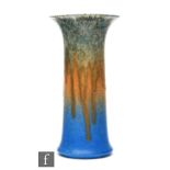 A Ruskin Pottery trumpet vase in a streaked green, orange and blue crystalline glaze, height 19cm.