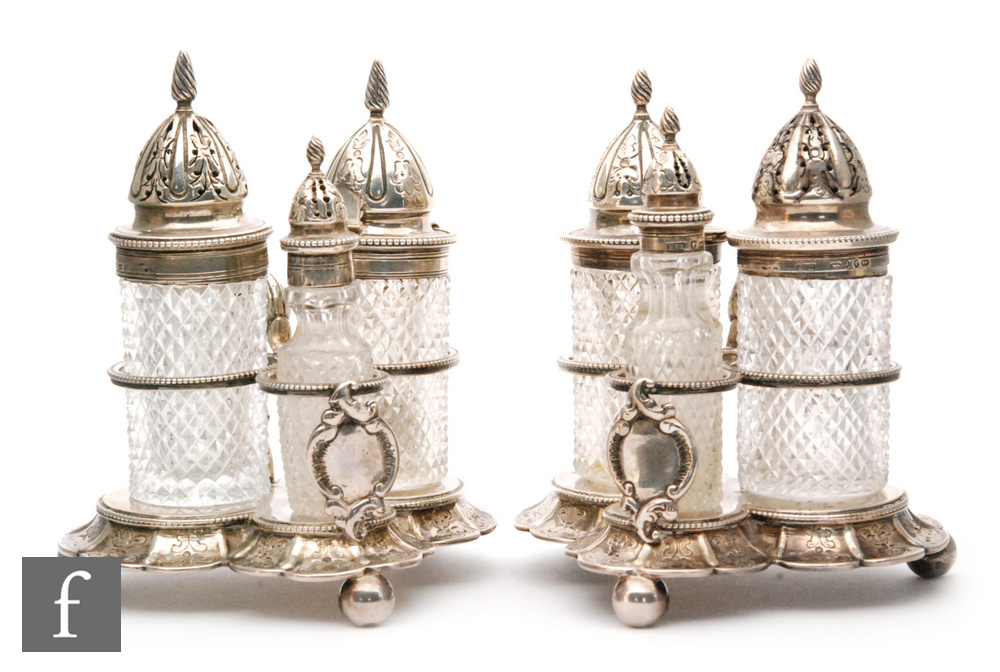A pair of hallmarked silver and clear glass three bottle cruets each with cylindrical diamond cut