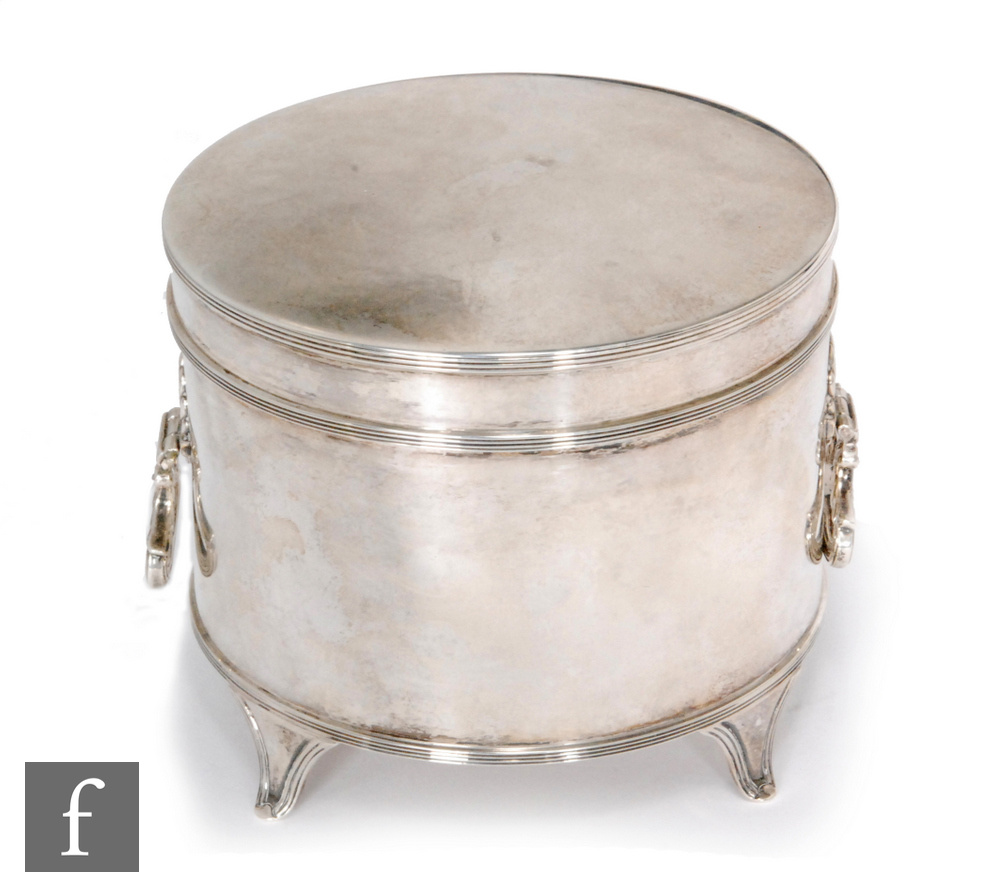 A hallmarked silver circular box of plain form terminating in twin drop ring handles and raised on