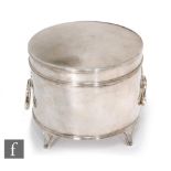 A hallmarked silver circular box of plain form terminating in twin drop ring handles and raised on