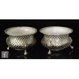 A pair of 19th Century open salts with milk glass liners, of white metal reticulated design and