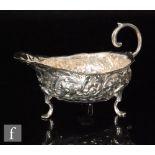 A 19th Century hallmarked silver sauce boat with embossed foliate decoration below flying scroll