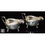 A pair of hallmarked silver sauce boats of plain form each with scroll handle and raised on three