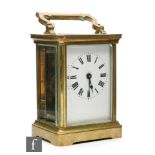 An early 20th Century brass carriage clock, Roman numerals to a rectangular white enamelled dial,