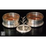 A pair of hallmarked silver circular bottle coasters each with wooden bases and pierced gallery