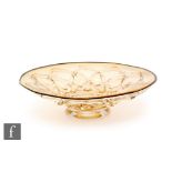 An early 20th Century amber glass bowl of footed shallow form, moulded with a diamond lattice