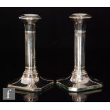 A pair of hallmarked silver candlesticks, canted square bases below plain columns and circular