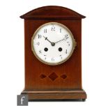 An Edwardian mahogany eight day strike mantle clock, Arabic numerals to a white enamelled dial below