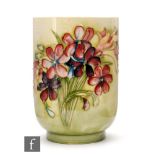 William Moorcroft - A footed cylindrical vase decorated in the Spring Flowers with a tubelined