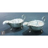 A pair of hallmarked silver sauce boats each raised on three stepped pad feet, Birmingham 1936, with