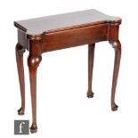 A George III mahogany fold over tea table, the shaped re-entrant top over a plain frieze on shaped