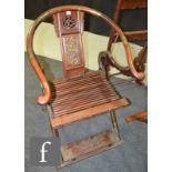 A Chinese 20th Century hardwood horseshoe-back folding chair with a carved openwork splat with