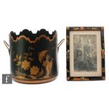 A 1920s Japanese lacquered photograph frame, decorated with figures and buildings on a black ground,