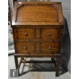 A small 1930s carved oak bureau, the fitted interior enclosed by a fall over two drawers on block